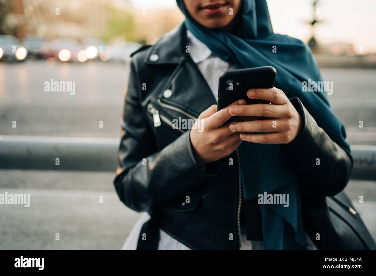 Crop muslimische Weibchen im Kopftuch stehen auf der Straße der Stadt und Durchsuchen des Mobiltelefons Stockfoto