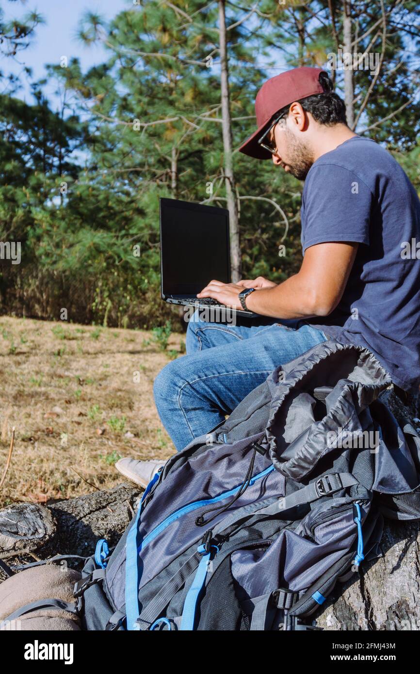 Von unten Nomade sitzt auf Stein in der Nähe von Habseligkeiten und mit Netbook bei Remote-Arbeit Stockfoto