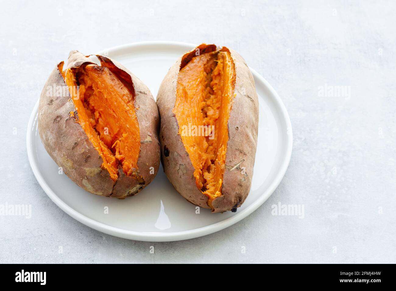 Von oben appetitlich frisch gebackene Süßkartoffeln auf Weiß gelegt Keramikuntertasse auf dem Tisch Stockfoto