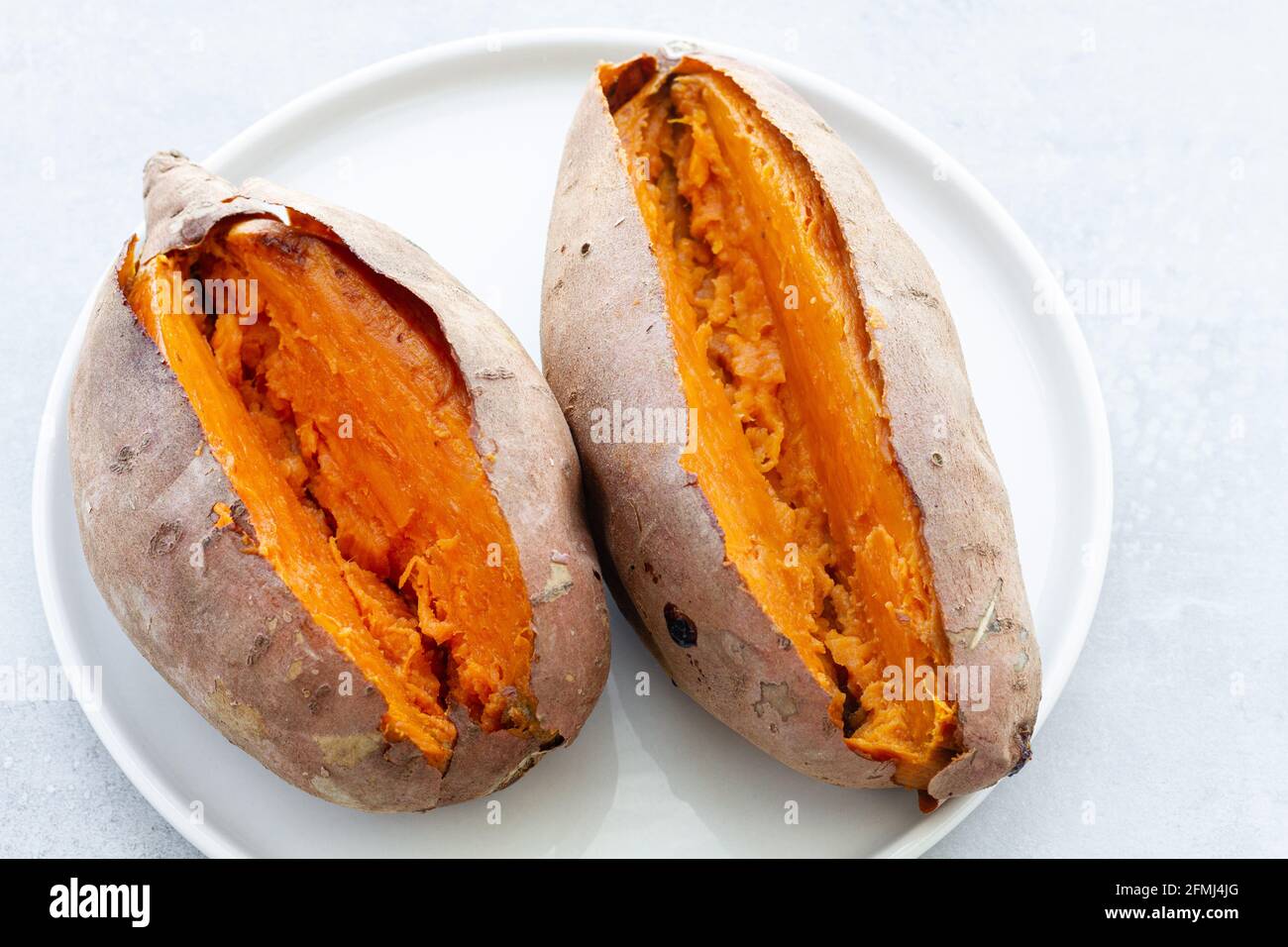 Von oben appetitlich frisch gebackene Süßkartoffeln auf Weiß gelegt Keramikuntertasse auf dem Tisch Stockfoto