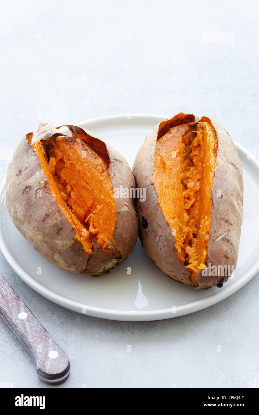 Von oben appetitlich frisch gebackene Süßkartoffeln auf Weiß gelegt Keramikuntertasse auf dem Tisch Stockfoto