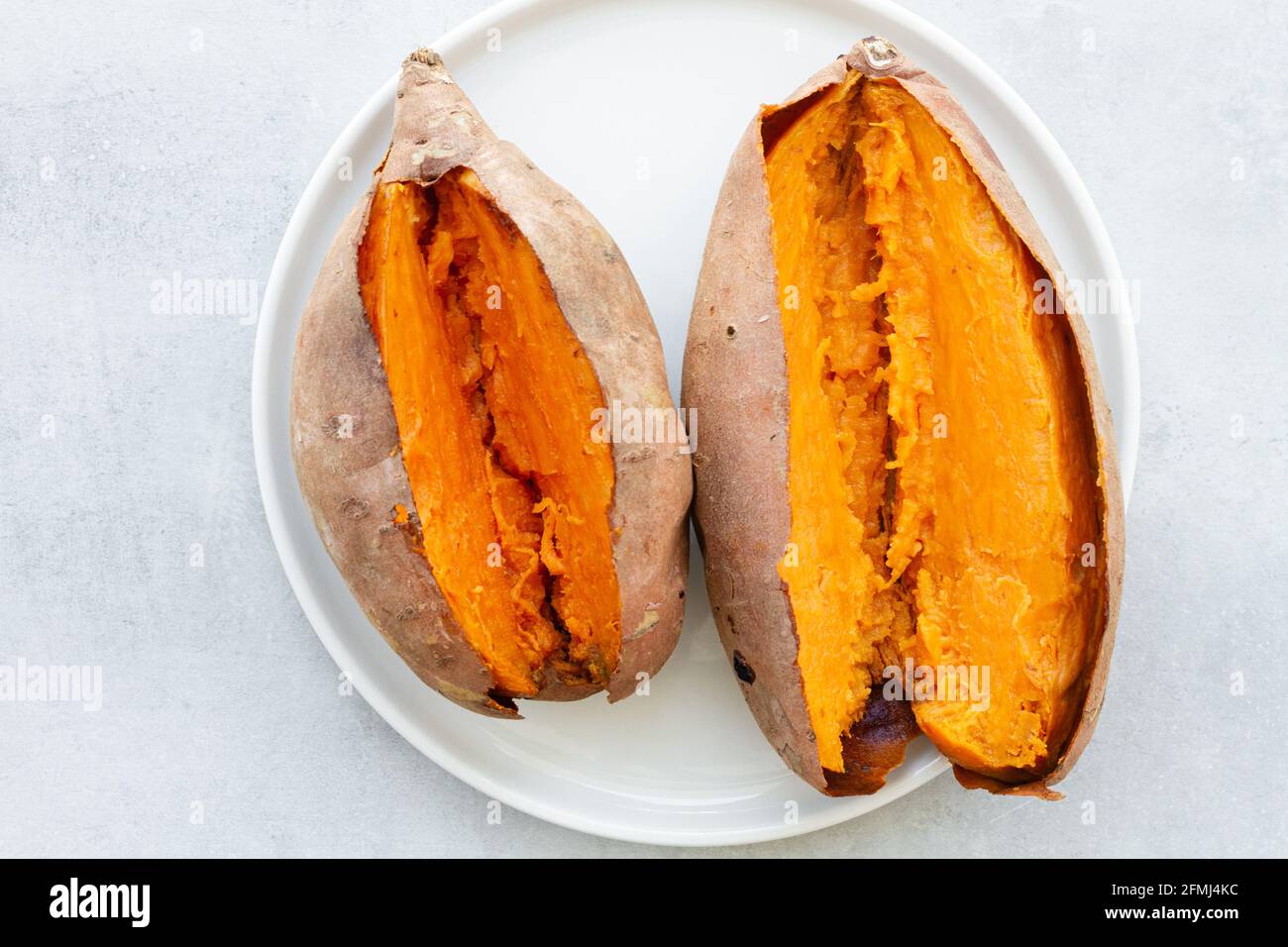 Von oben appetitlich frisch gebackene Süßkartoffeln auf Weiß gelegt Keramikuntertasse auf dem Tisch Stockfoto