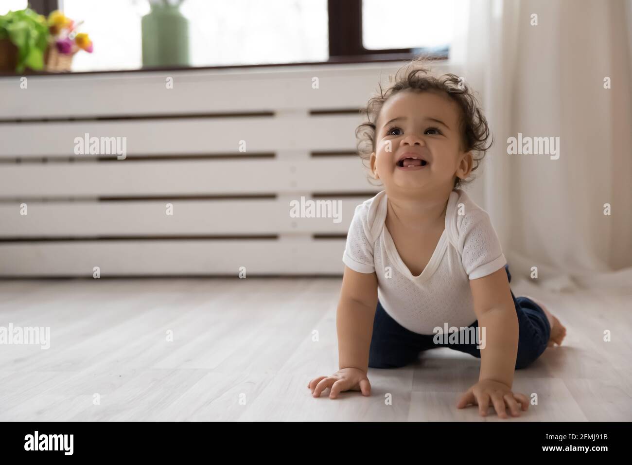 Lächelndes afroamerikanisches Kleinkind, das auf dem Boden kriecht Stockfoto