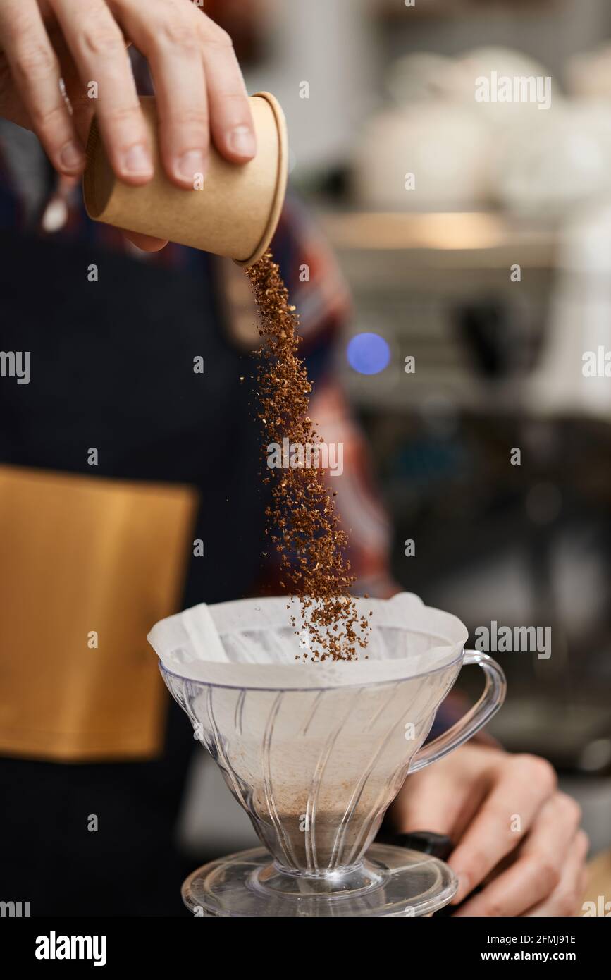 Männliche Hände gießen gemahlenen Kaffee in den Filter. Stockfoto