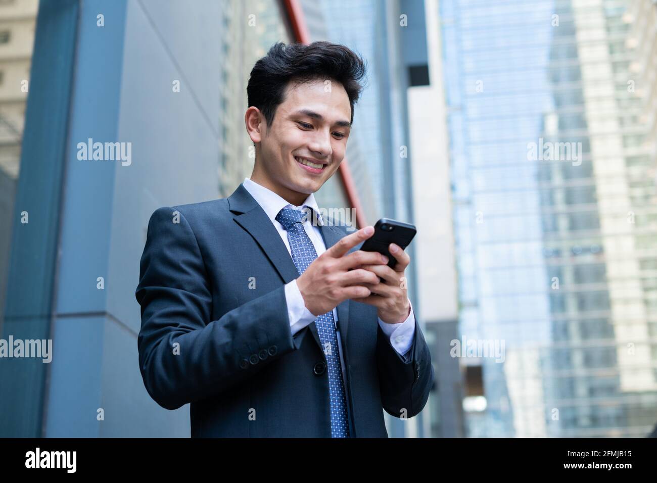 Junger asiatischer Geschäftsmann mit Smartphone, um eine SMS zu senden Stockfoto