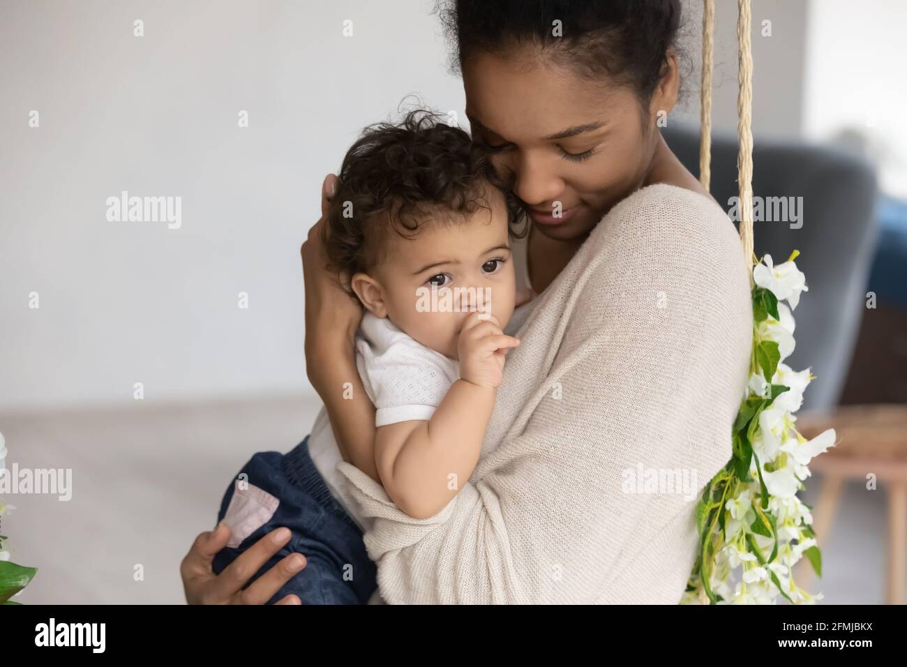Fürsorgliche afroamerikanische Mutter kuscheln Baby Tochter Stockfoto