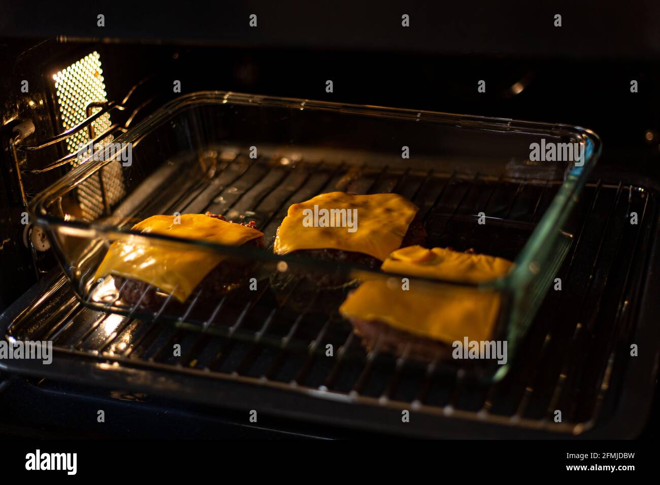 Burger Hackfleisch mit Cheddar-Käse im Ofen bedeckt. Prozess der Burger Kochen zu Hause. Stockfoto