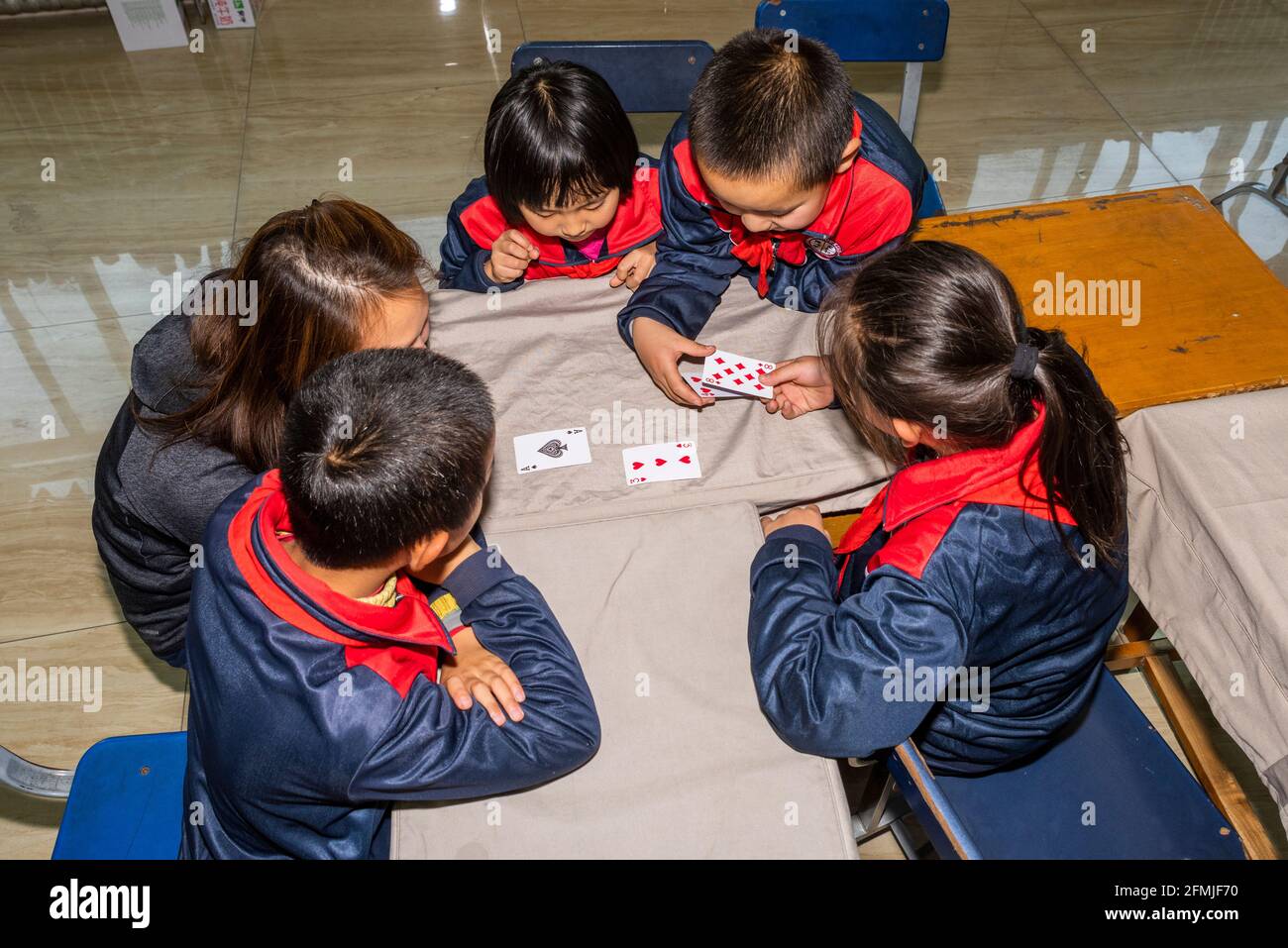 Der Lehrer beschäftigt sich mit den Schülern während eines Make-24-Kartenspiels An der BOAI Schule in Shanxi Stockfoto