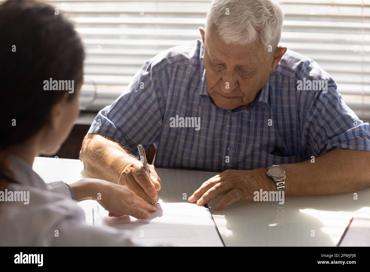 Pensionierter Mann unterzeichnet Gesundheitsdienstvertrag bei Arztpraxis Stockfoto