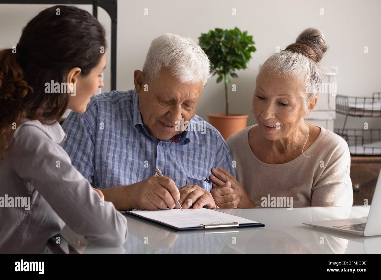 Pensionierte Ehegatten unterzeichnen Papiervertrag mit Hilfe eines professionellen Agenten Stockfoto