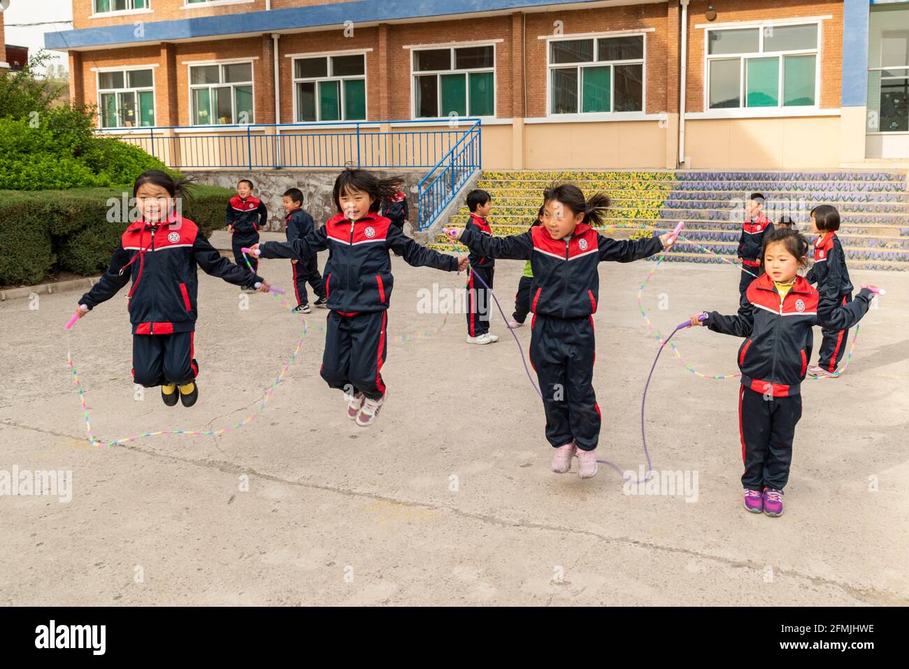Schüler springen während ihrer Pause an der BOAI-Schule in Shanxi, China, Seil Stockfoto