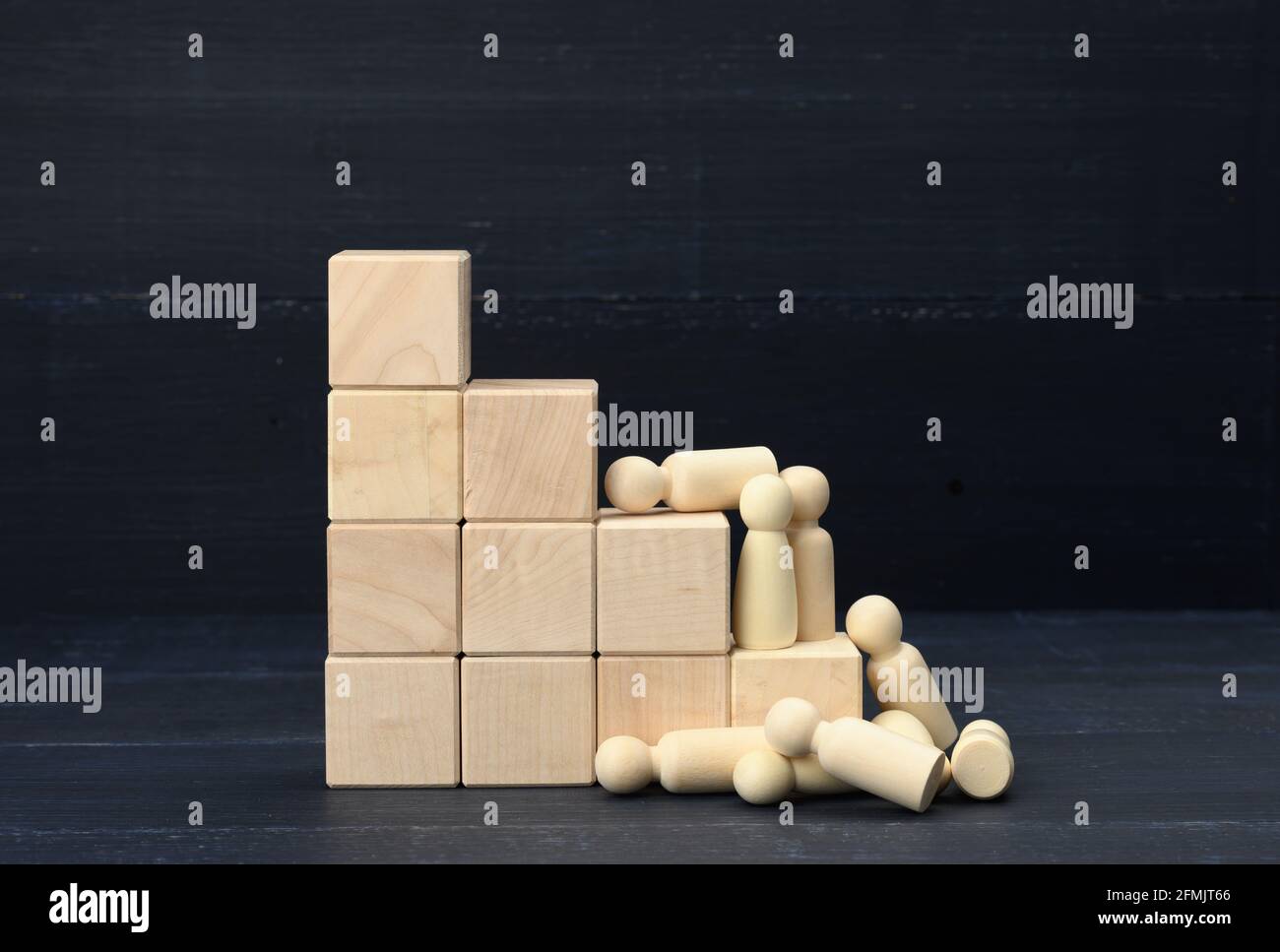 Treppen aus Holzwürfeln und eine Menge gefallener Holzfiguren von Männern auf blauem Hintergrund. Das Konzept des Wettbewerbs in der Wirtschaft, Karriere. Burnout in Stockfoto