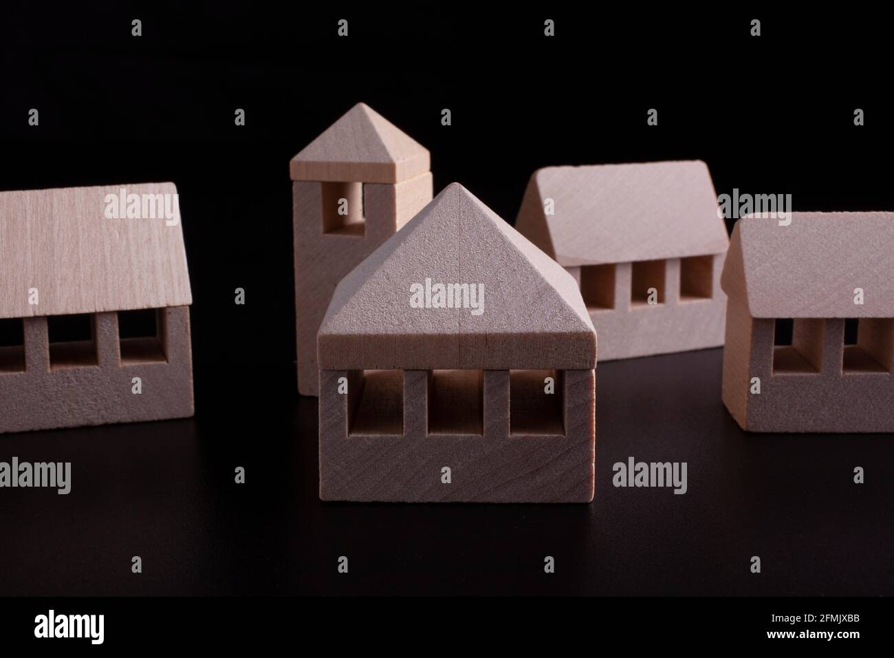 Hölzerne Miniaturhäuser auf schwarzem Hintergrund - Immobilien Konzept Stockfoto