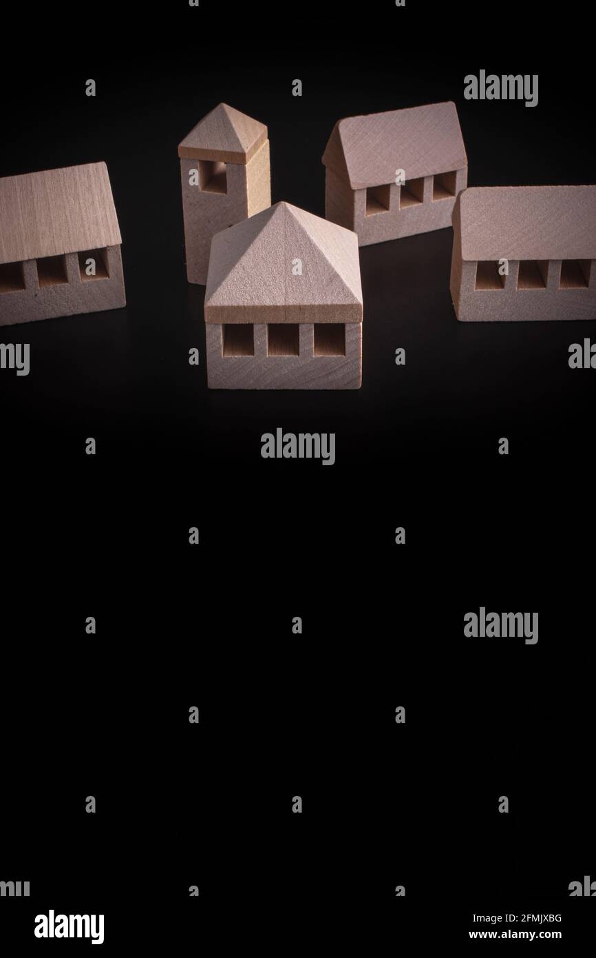 Hölzerne Miniaturhäuser auf schwarzem Hintergrund - Immobilien Konzept Stockfoto