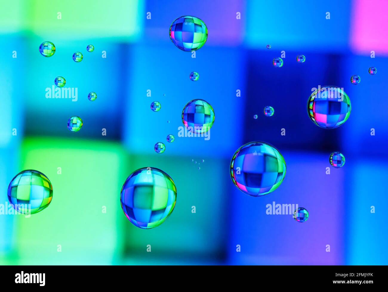 Schöne farbige Beugungseffekte von Wassertröpfchen auf Glas gegen Ein mehrfarbiger Hintergrund Stockfoto