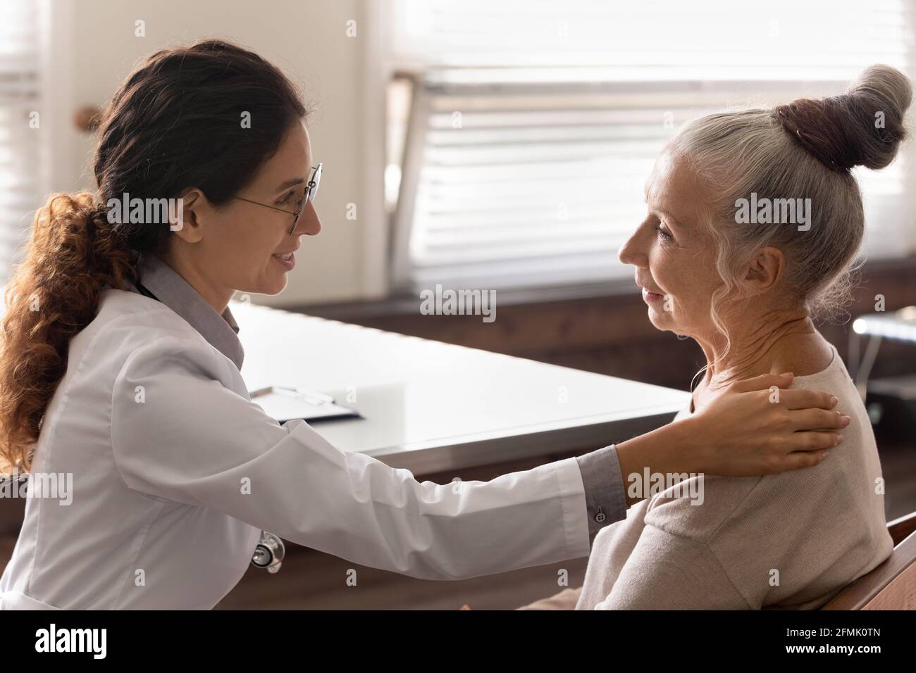 Frau gp sprechen mit reifen Dame Hand auf Schulter halten Stockfoto