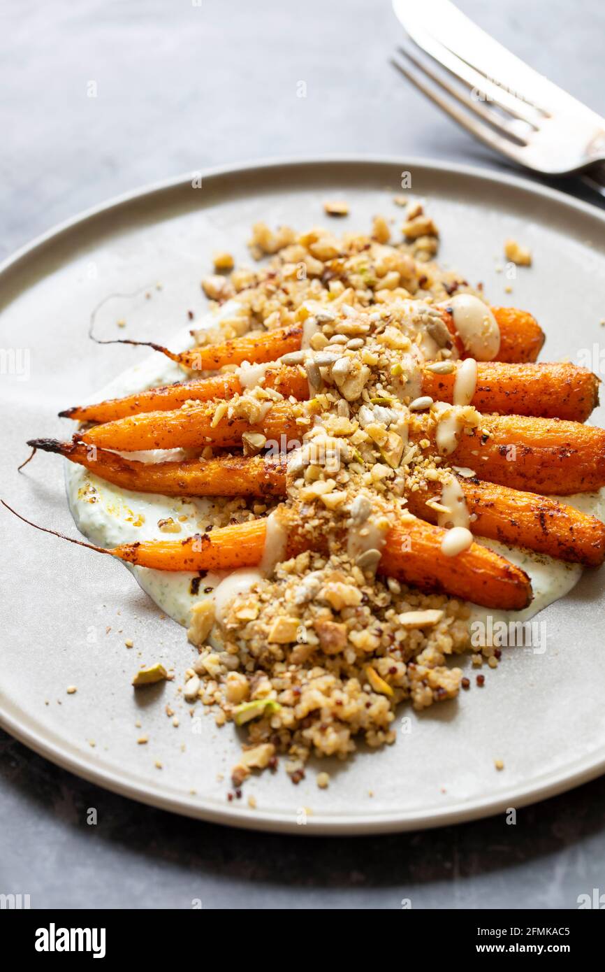 Kreuzkümmel gewürzte Braten Karotten mit Dukkah, Quinoa und Knoblauchsoße Stockfoto