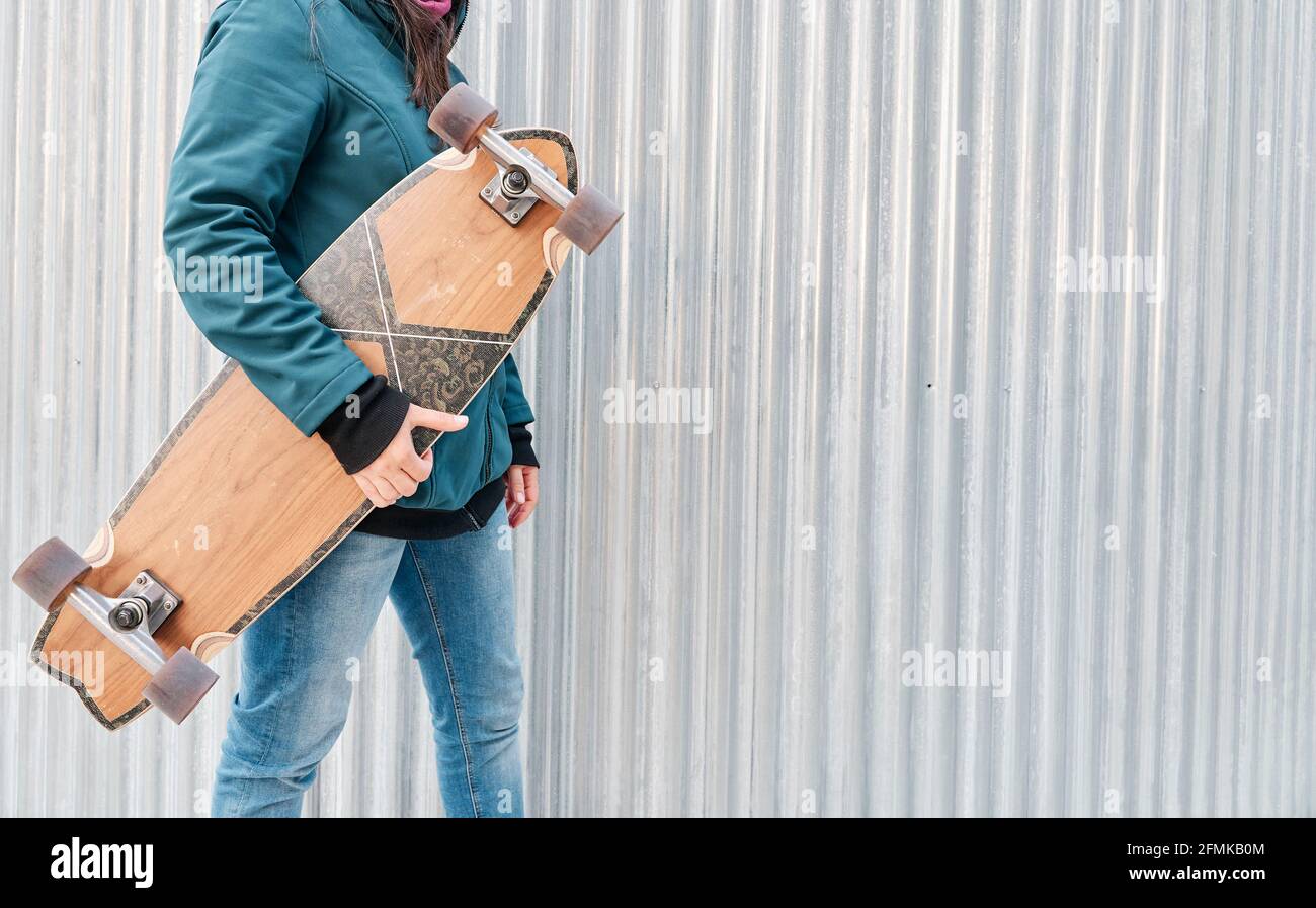 Gesichtsloses Mädchen, das ihr Skateboard hält. Platz für Text kopieren. Konzept des nachhaltigen Transports und einer gesunden Lebensweise. Stockfoto