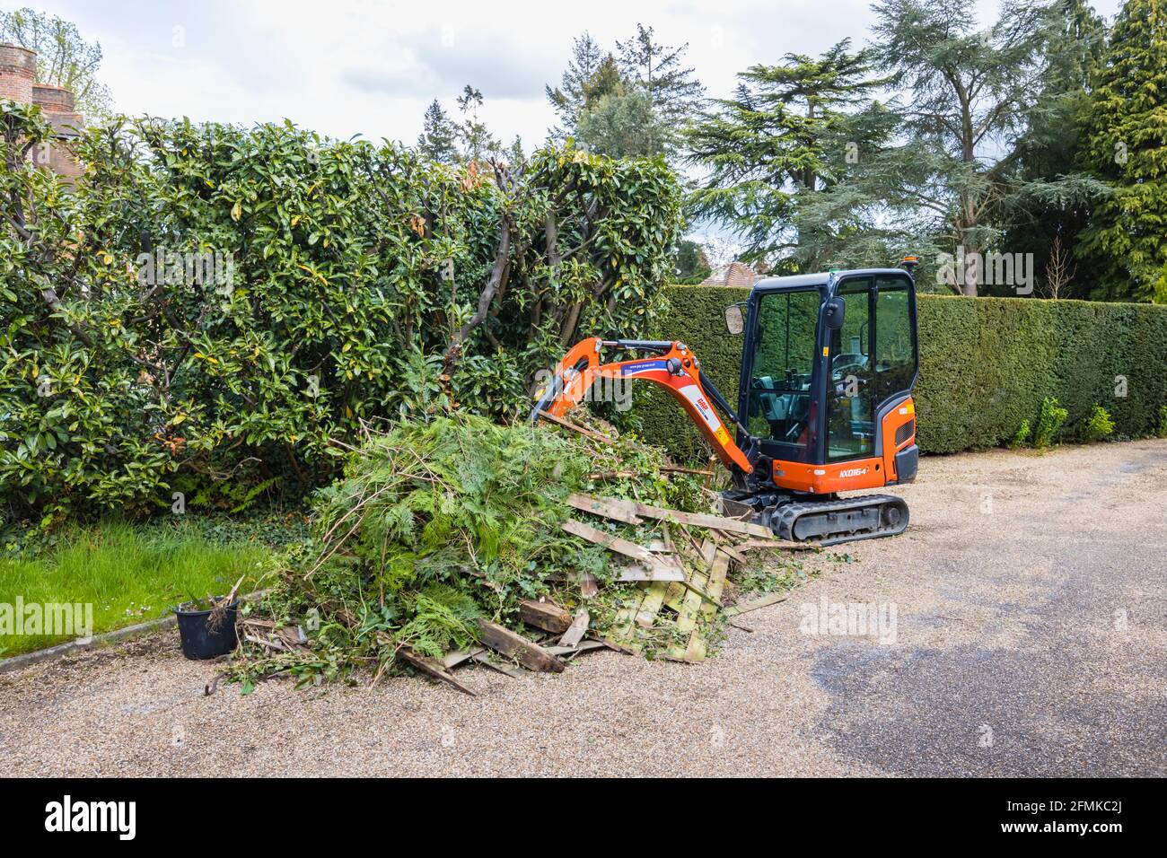 Ein Gummi-Raupenfahrzeug, ein orangefarbener Minibagger Kubota KX016-4, der für die Gartenräumung und die Beseitigung von Schutt verwendet wird, Surrey, England Stockfoto