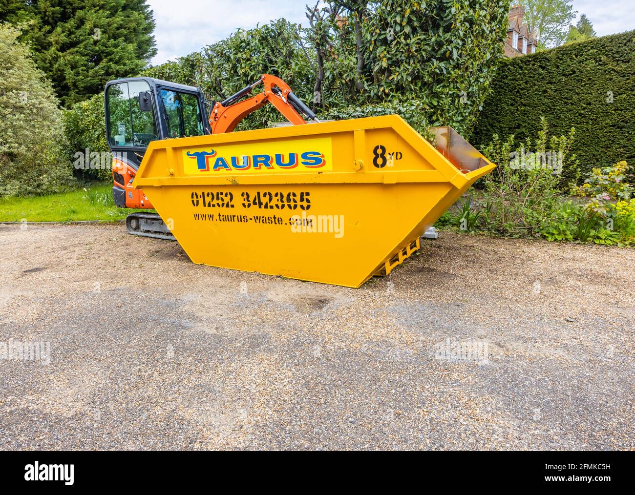 Ein Gummifahrzeug mit Raupen, ein orangefarbener Minibagger Kubota KX016-4 und ein gelber überlauf, der für die Gartenreinigung und die Beseitigung von Schutt verwendet wird, Surrey, England Stockfoto