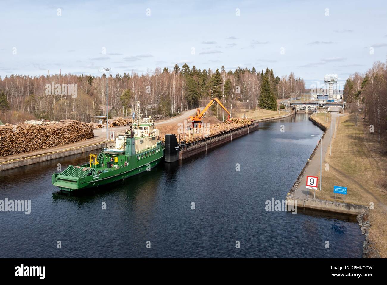 Im Ladebereich des Kanals in Varkaus, einer Stadt der Holzindustrie, wird eine Holzladung auf die Schubkahn verladen. Stockfoto