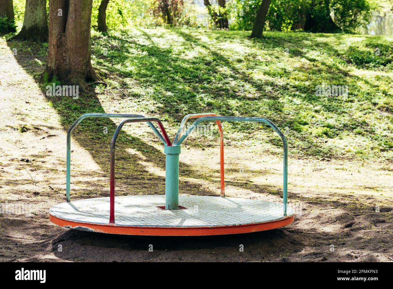 Roter und mintfarbener Spielplatz, Karussell gegen Bäume und Pflanzen Stockfoto