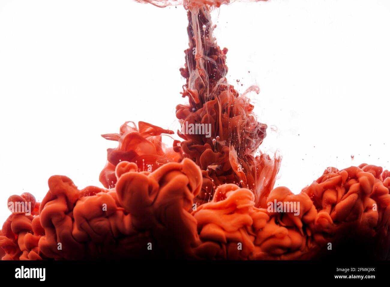 Tinte in Wasser. Abstrakter Hintergrund. Tinte wirbelt in Wasser. Tinte in Wasser isoliert auf weißem Hintergrund. Orangefarbene Tinte im Wasser. Stockfoto