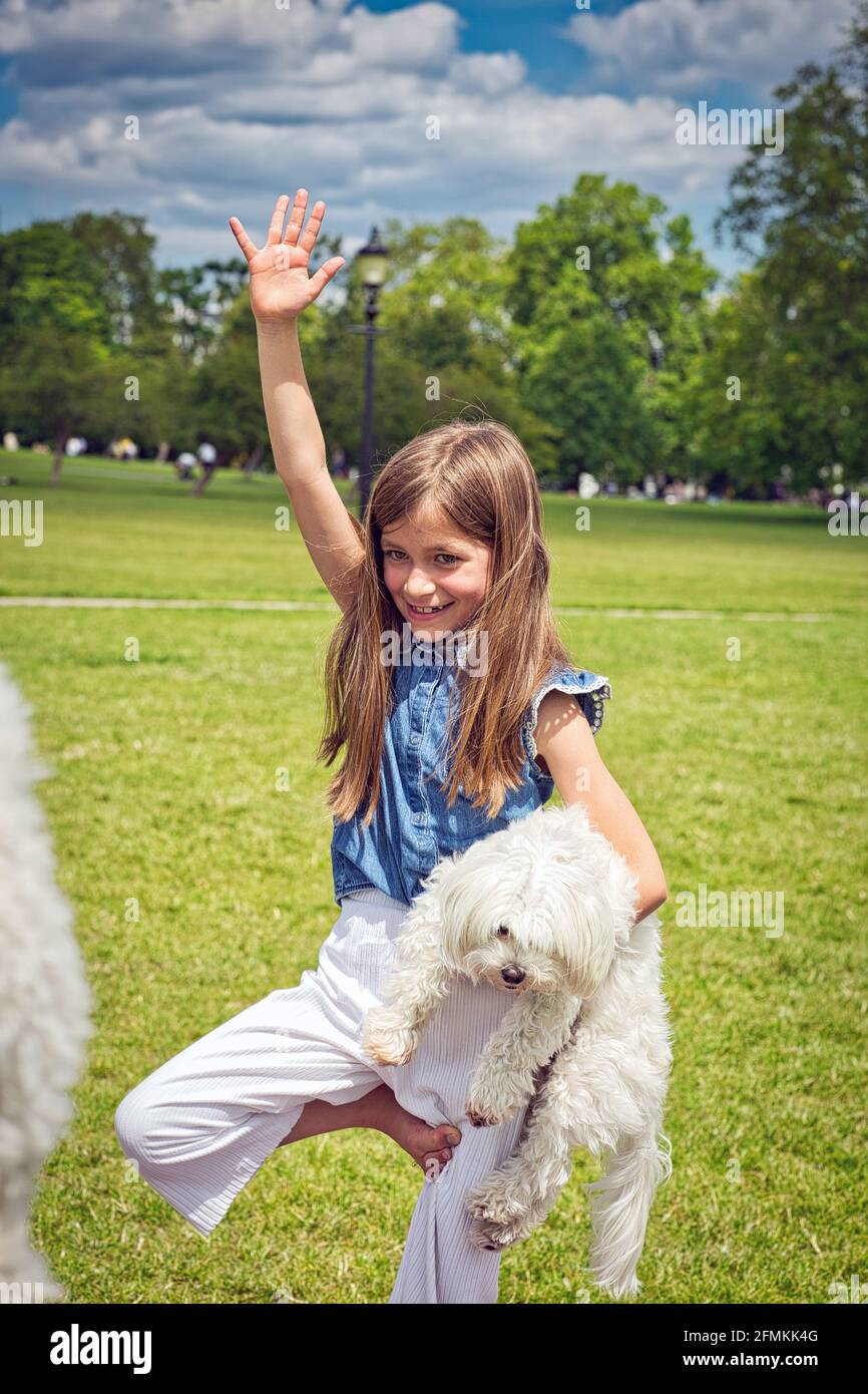 Mädchen mit Hund tut Yoga-Übungen in der Natur im Freien auf Grünes Gras auf der Fitnessmatte, Primerose Hill Park, London, Großbritannien Stockfoto