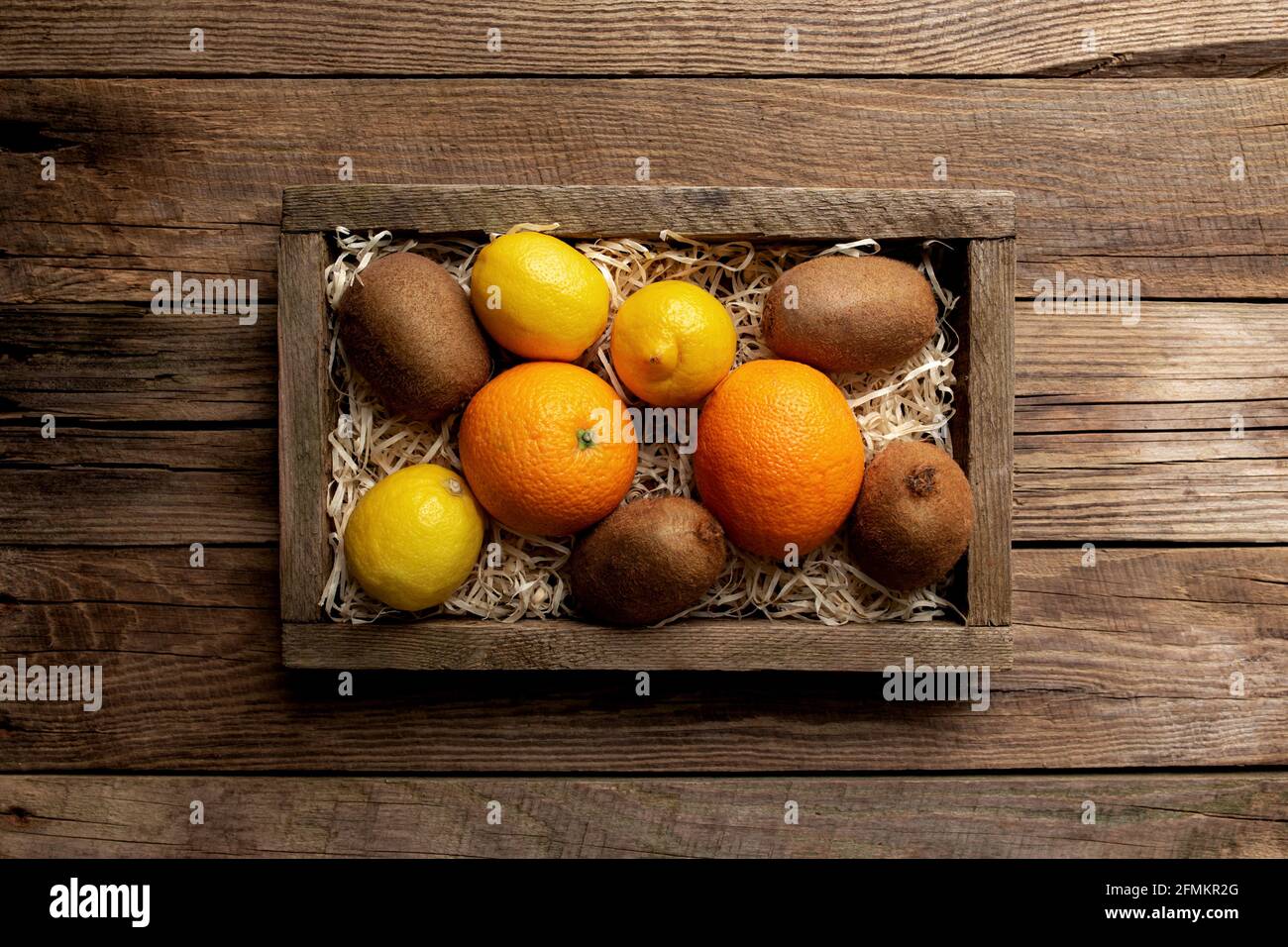 Frische tropische Früchte in einem Holzlieferkarton auf einem Holzhintergrund. Orange, Kiwi und Zitrone Draufsicht flach lag mit Kopieplatz für einige Werbung Stockfoto