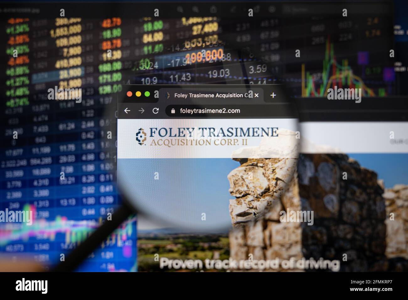 Foley Trasimene Firmenlogo auf einer Website mit verschwommenen Börsenentwicklungen im Hintergrund, gesehen auf einem Computerbildschirm Stockfoto