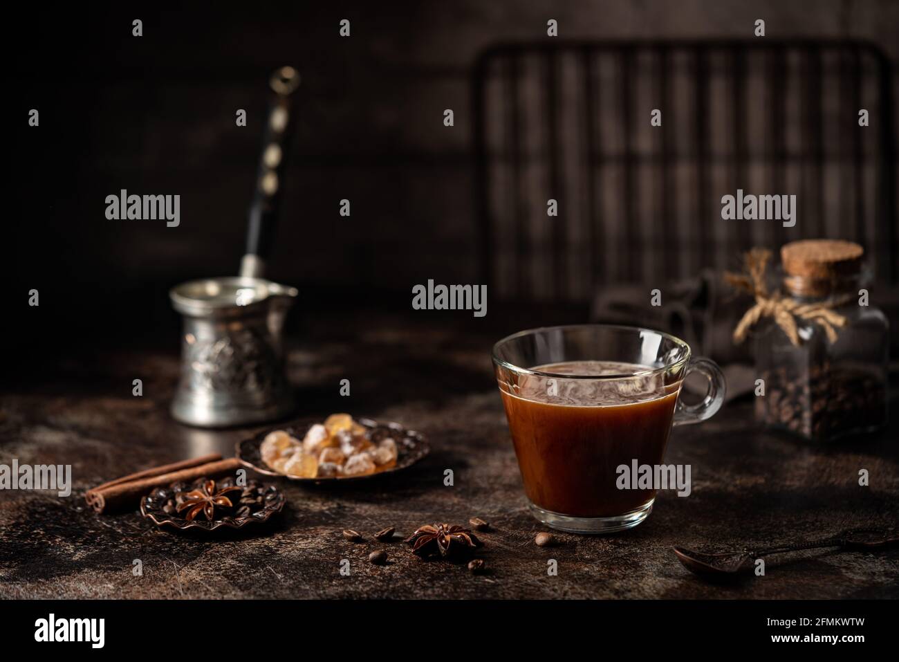 Kaffee in einem Glas mit Zucker und Kaffeebohnen auf Dunkler Hintergrund Stockfoto