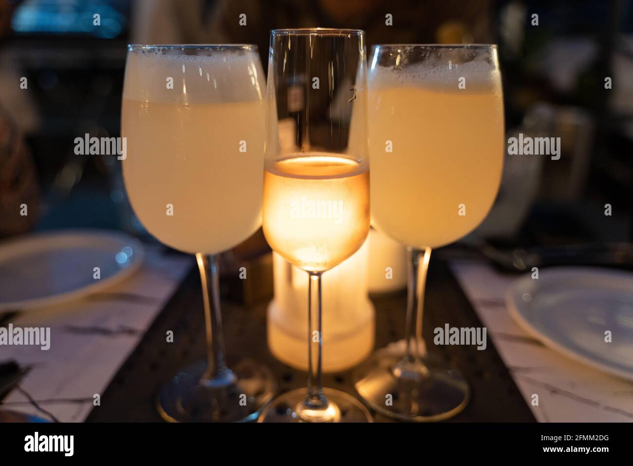 Glas Roséwein zwischen Pisco sauer großen Gläsern mit Kerzenlicht dahinter. Ausgefallenes Restaurant, Abendessen, Getränke, Feier Konzepte Stockfoto