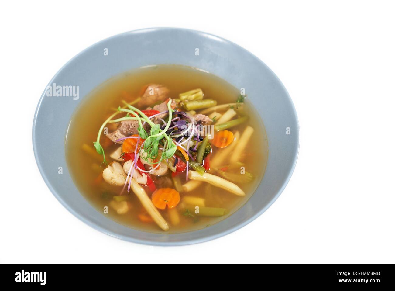 Nahaufnahme des blauen Tellers mit einer gesunden, appetitlichen Gemüsesuppe. Konzept der Suppe mit verschiedenen Gemüsesorten zur Aufrechterhaltung des Gewichts und der Körperform. Stockfoto