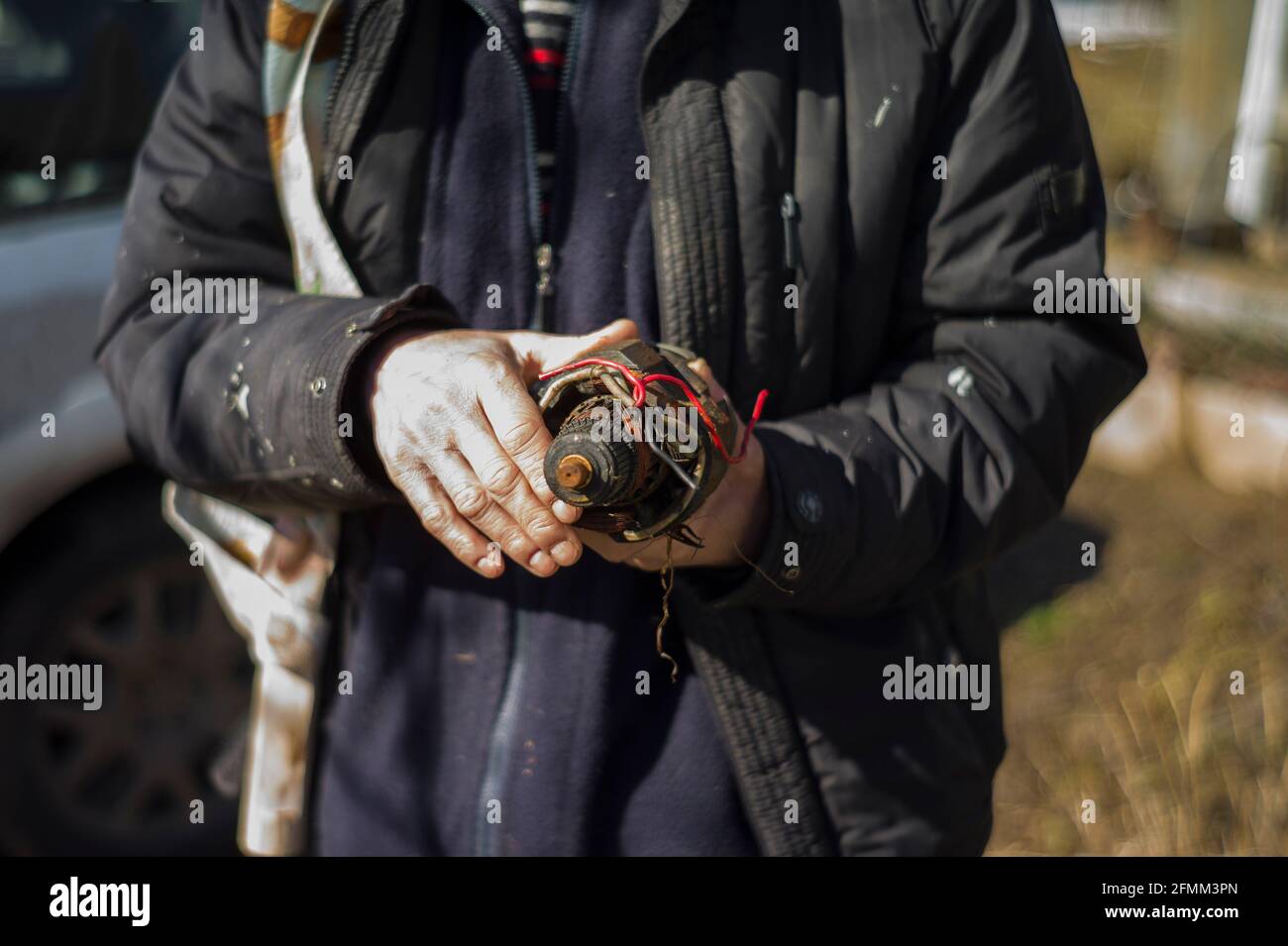 Hände eines Metallschrottsammlers mit einem Stück Elektromotor, flacher Freiheitsgrad Stockfoto