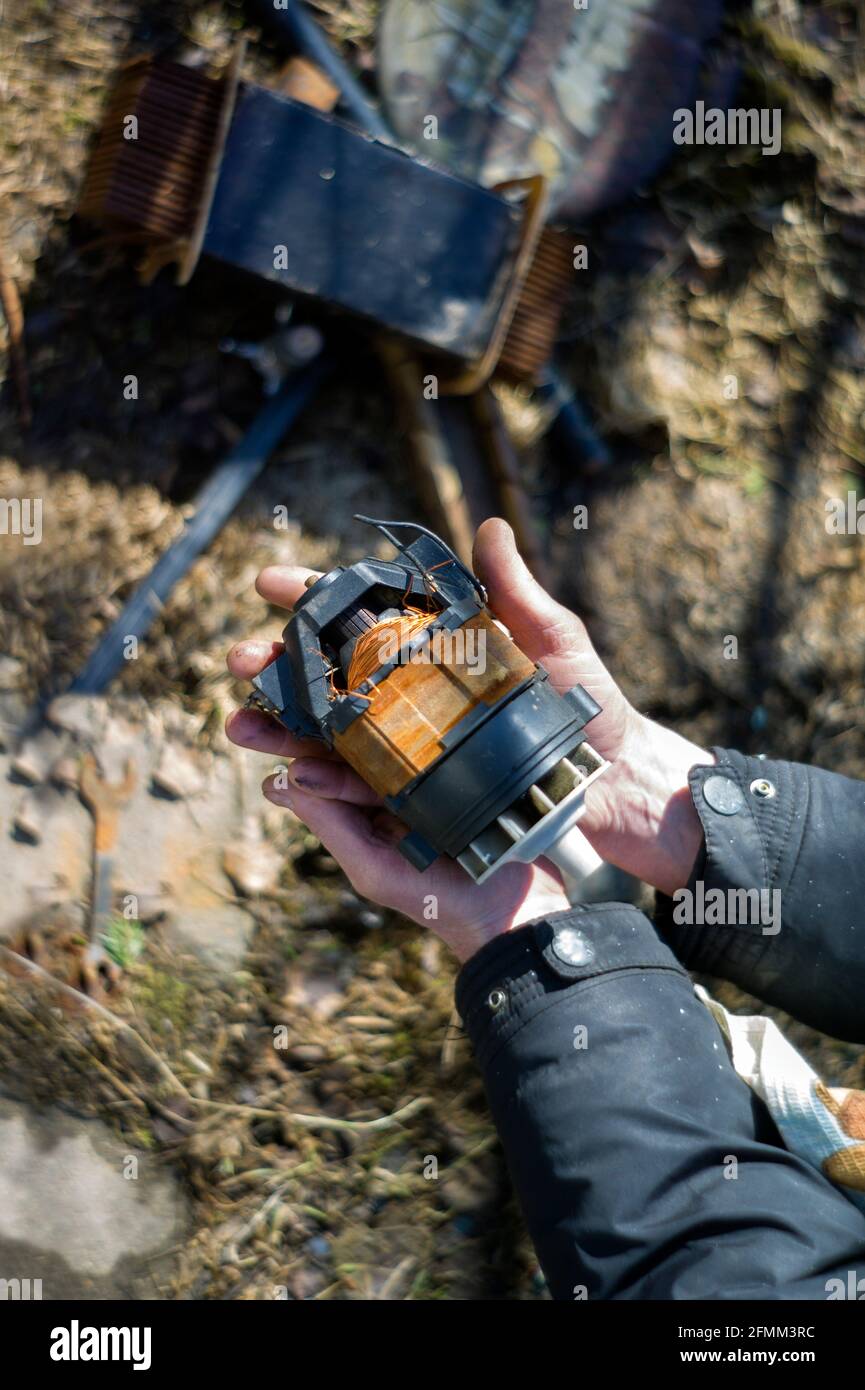 Hände eines Metallschrottsammlers mit einem Stück Elektromotor, flacher Freiheitsgrad. Vertikale Aufnahme Stockfoto