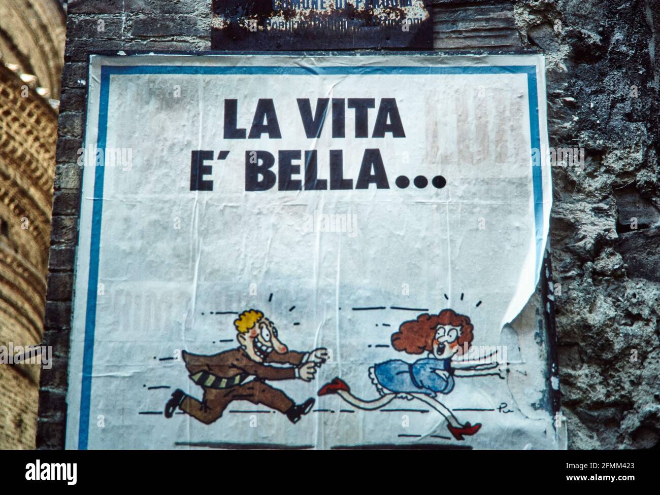 Poster an einer Wand in Perugia: La Vita E' Bella - das Leben ist schön. Ein Mann läuft einer Frau hinterher. 1984 - Christoph Keller Stockfoto