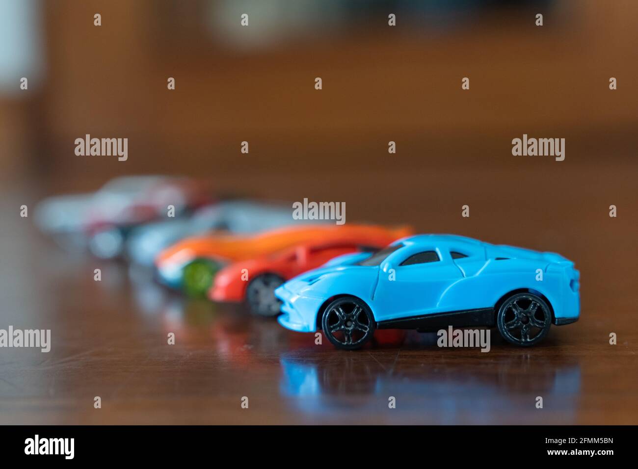 Gruppe von Spielzeugautos in verschiedenen Farben mit blauem Sport auf der Vorderseite. Wettkämpfe, Sammlungskonzepte Stockfoto