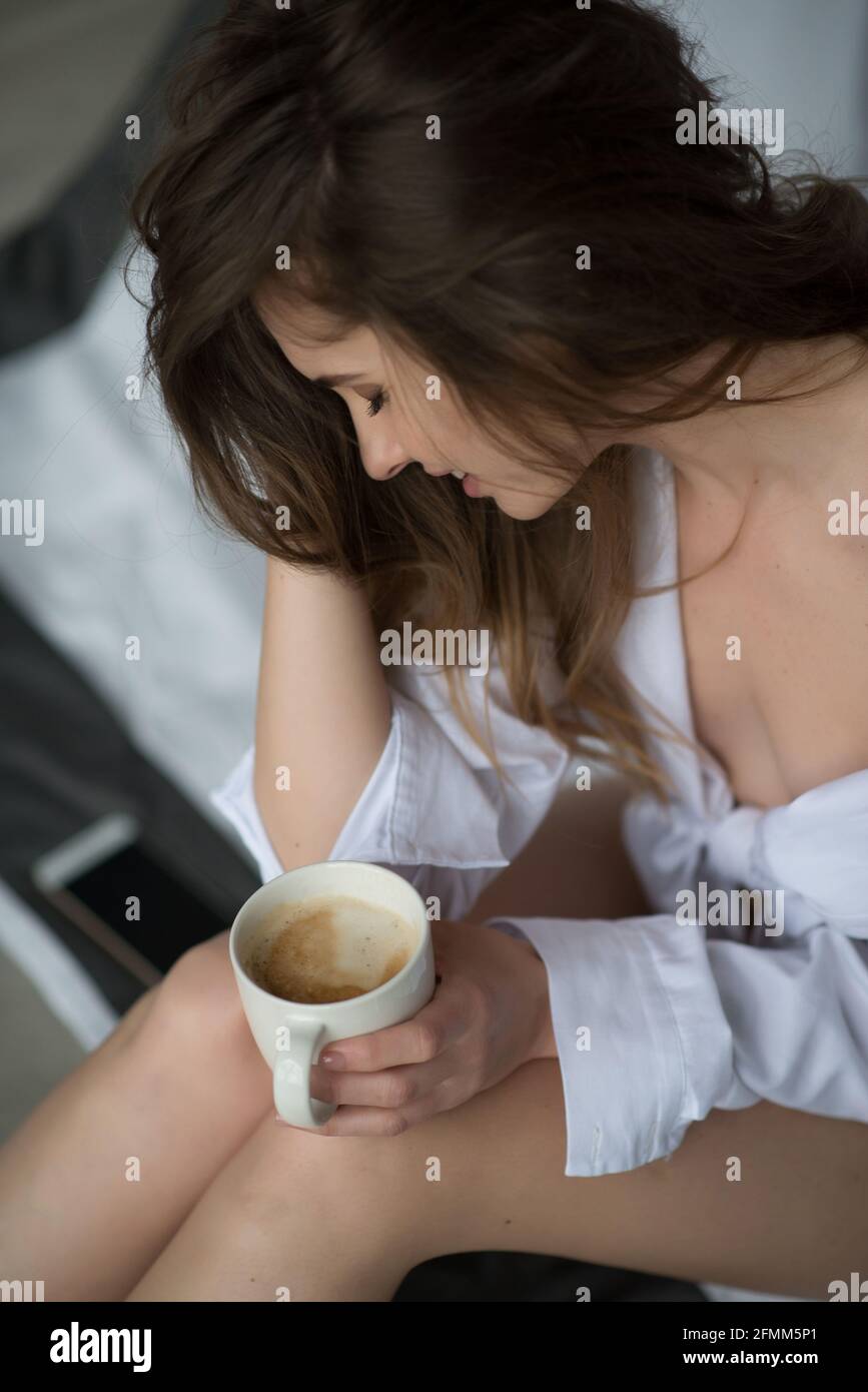 Junge schöne Mädchen am Morgen mit einer Tasse Kaffee im Loft-Schlafzimmer. Weicher, selektiver Fokus. Stockfoto