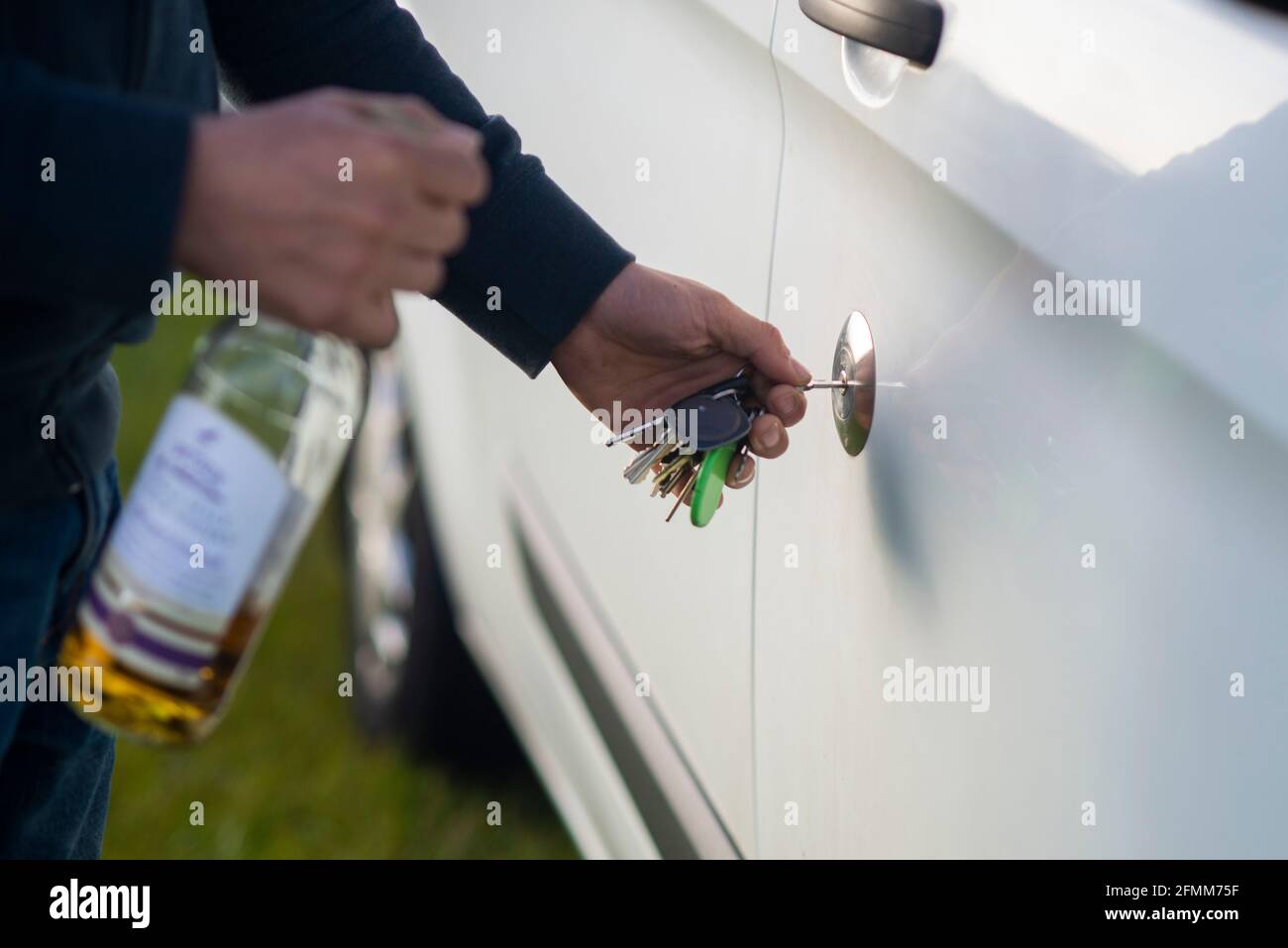 Betrunken in der Leitung eines Wohnmobils Wohnmobil. Ein Mann entriegelt seine Van-Tür mit einer Flasche Whisky-Alkohol in der Hand. Trinken fahren England Großbritannien Stockfoto