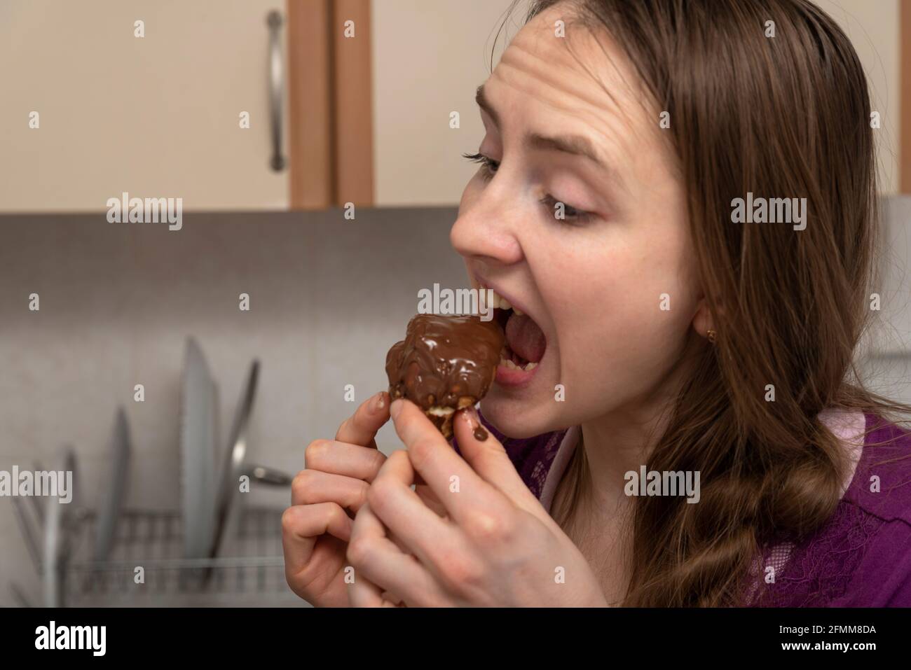 Mädchen isst gierig einen Schokoladenkuchen. Ende der Diät. Stockfoto