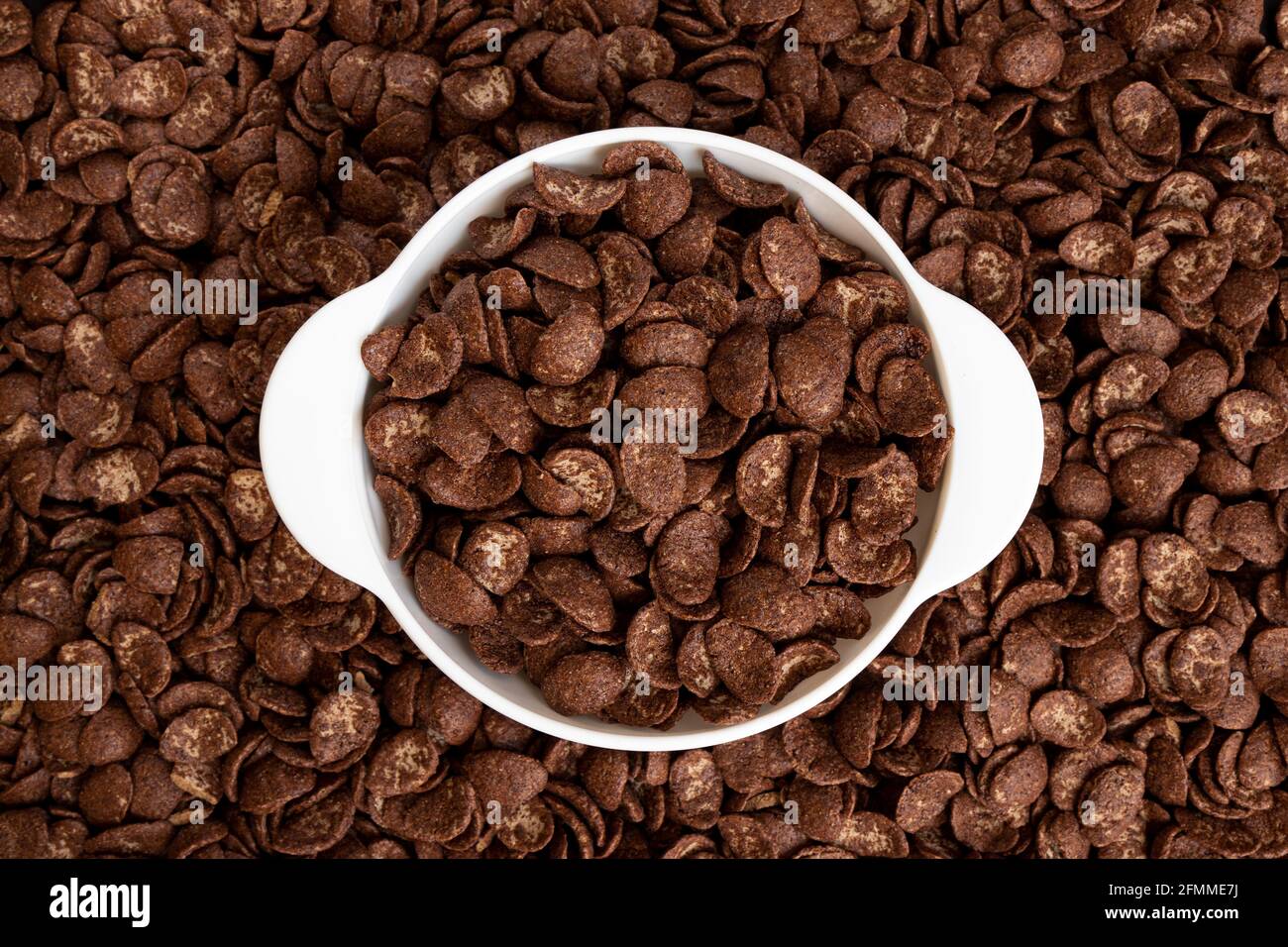 Schokoladenflocken in Schale auf Flakes Hintergrund, gesundes Frühstückskonzept, Teller Cornflakes Stockfoto