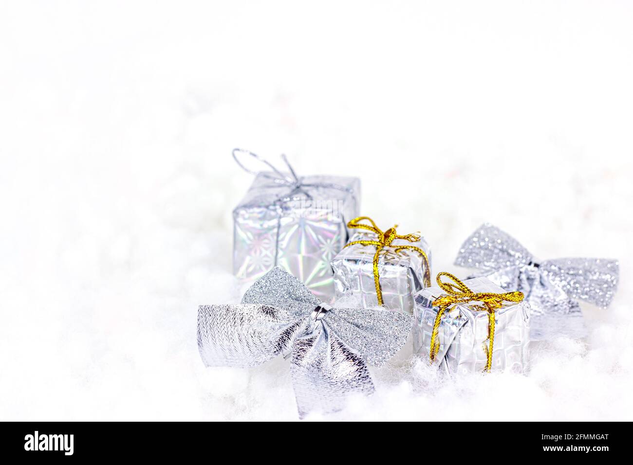 Helle silberne Weihnachtsdekorationen (Bänder, Geschenke, Geschenkboxen) auf weißem Kunstschneegrund mit Kopierfläche. Weihnachten und Neujahr traditionell Stockfoto