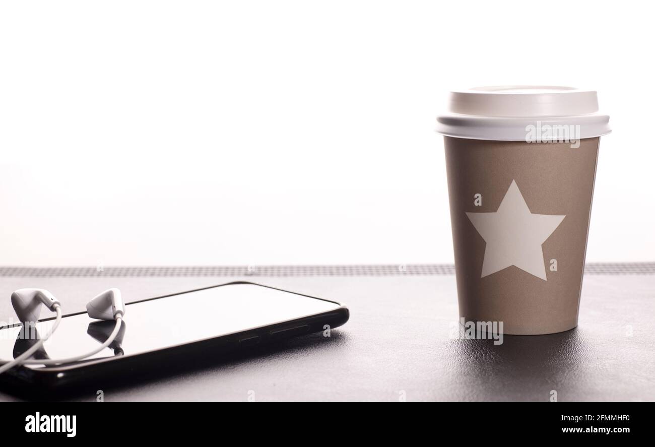 Einweg- und recycelbare Teetasse mit Stern, Telefon mit Kopfhörern, weißer Hintergrund Stockfoto
