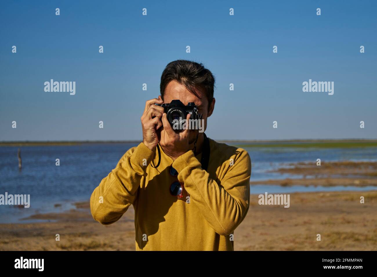 Weißer Mann, der mit einer alten Kamera auf dem Feld fotografiert Stockfoto