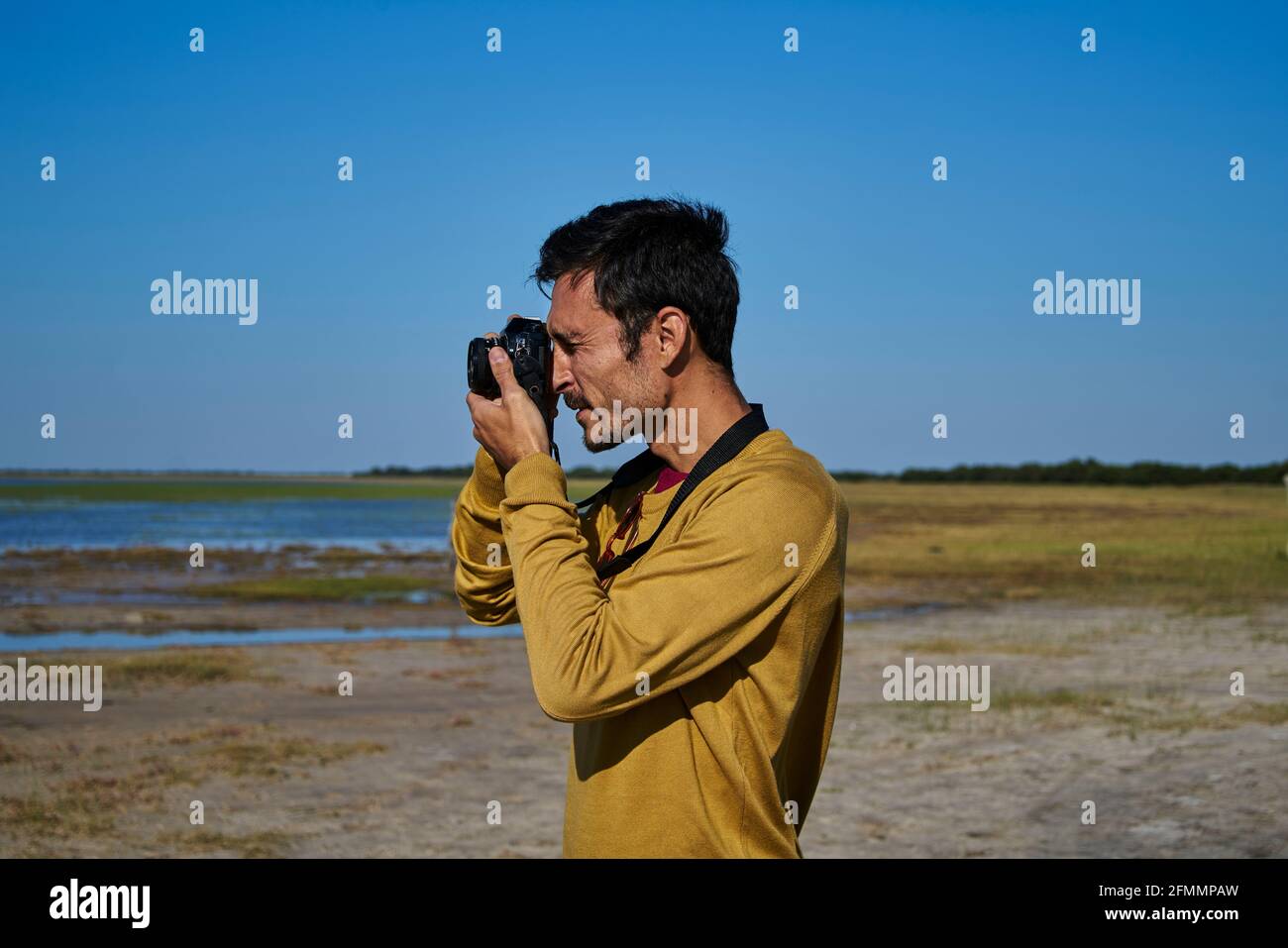 Weißer Mann, der mit einer alten Kamera auf dem Feld fotografiert Stockfoto