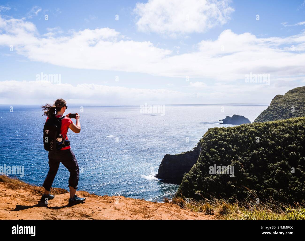 Frau macht Handy-Foto, während sie in der Nähe des Ozeans in wandern Hawaii Stockfoto