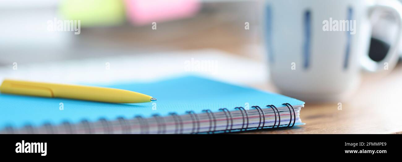 Auf dem Tisch ist Tasse neben Stift und Tagebuch für Hinweise Stockfoto