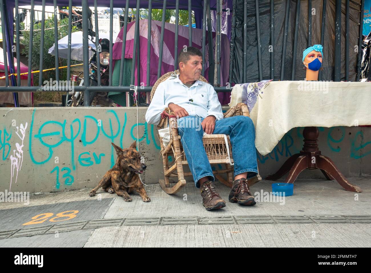 Medellin, Antioquia, Kolumbien - März 27 2021: Ein fauler Latein, der auf einem Stuhl sitzt, pettt seinen braunen Hund Mongrel Stockfoto