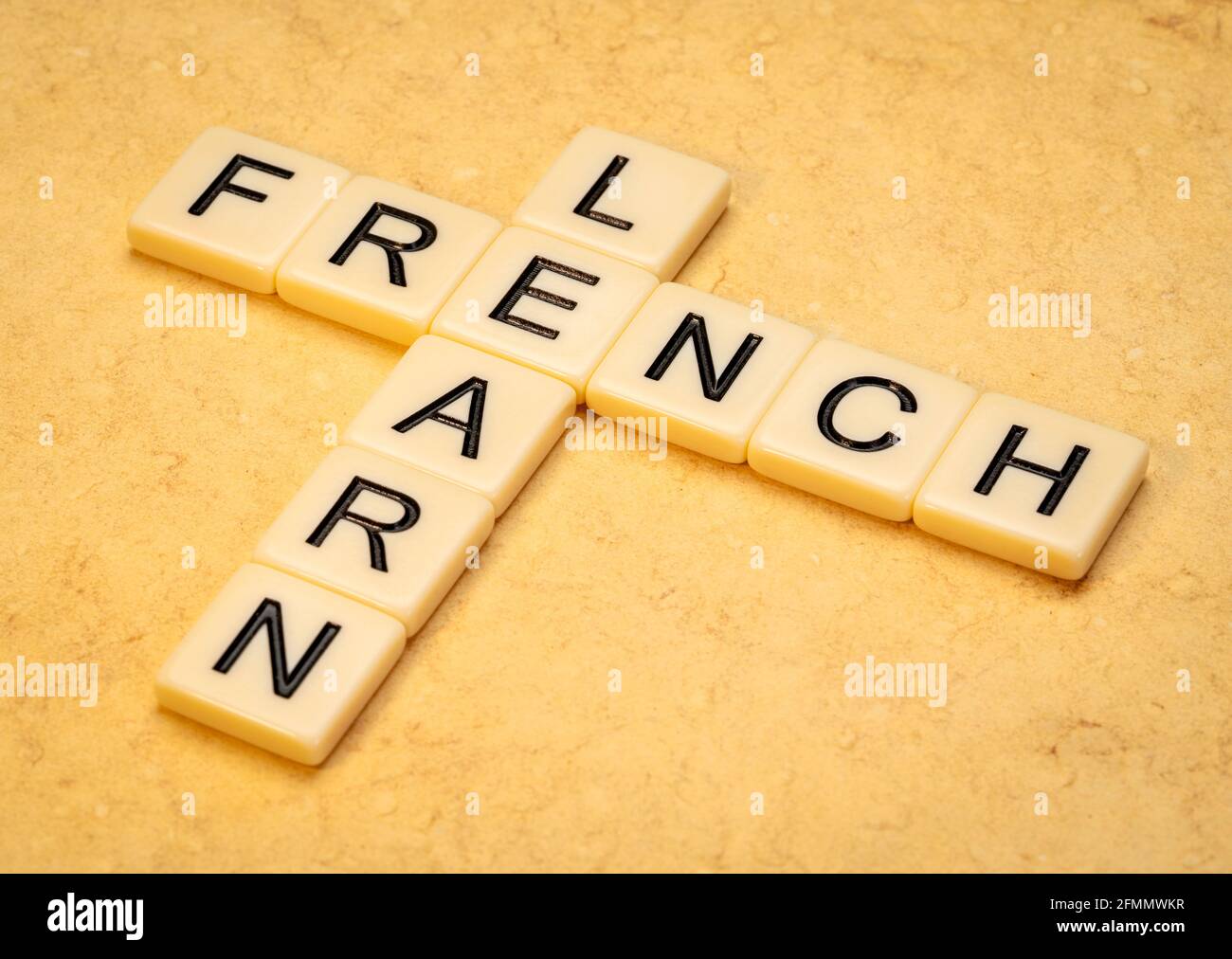 Lerne Französisch Kreuzworträtsel in Elfenbein Buchstaben Kacheln gegen gelb strukturiert Papier Stockfoto