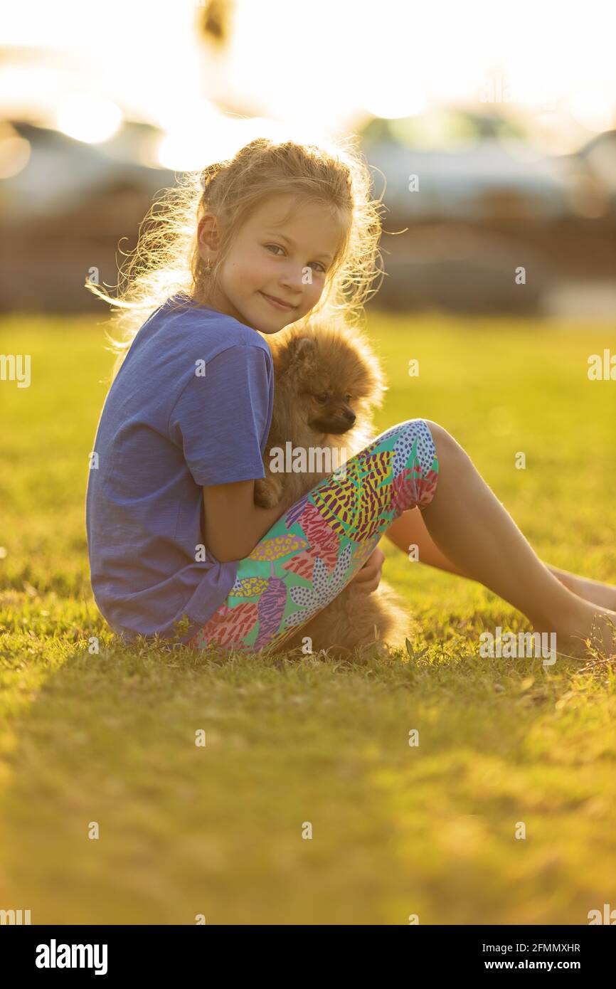 Kleines Mädchen hält Welpen. Kind mit Hund. Familie und Haustiere auf Parkrasen. Kinder- und Tierfreundschaften Stockfoto